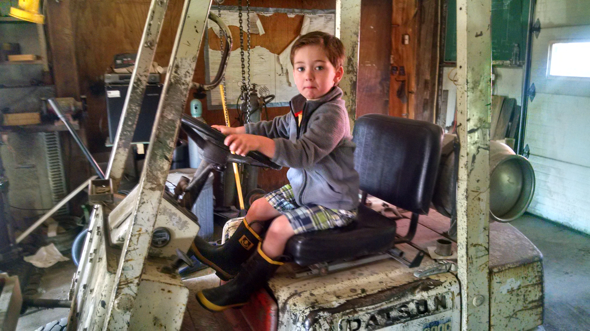 Casen sitting on the old Datsun forklift in the shop