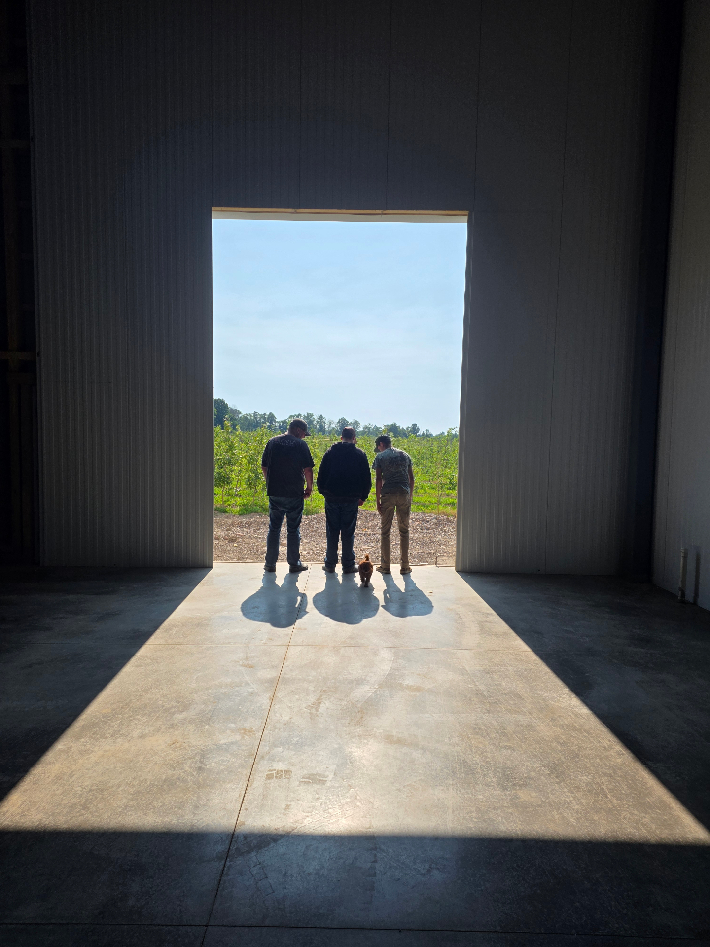 Jason and his boys standing in the CA storage doorway looking out at a young orchard