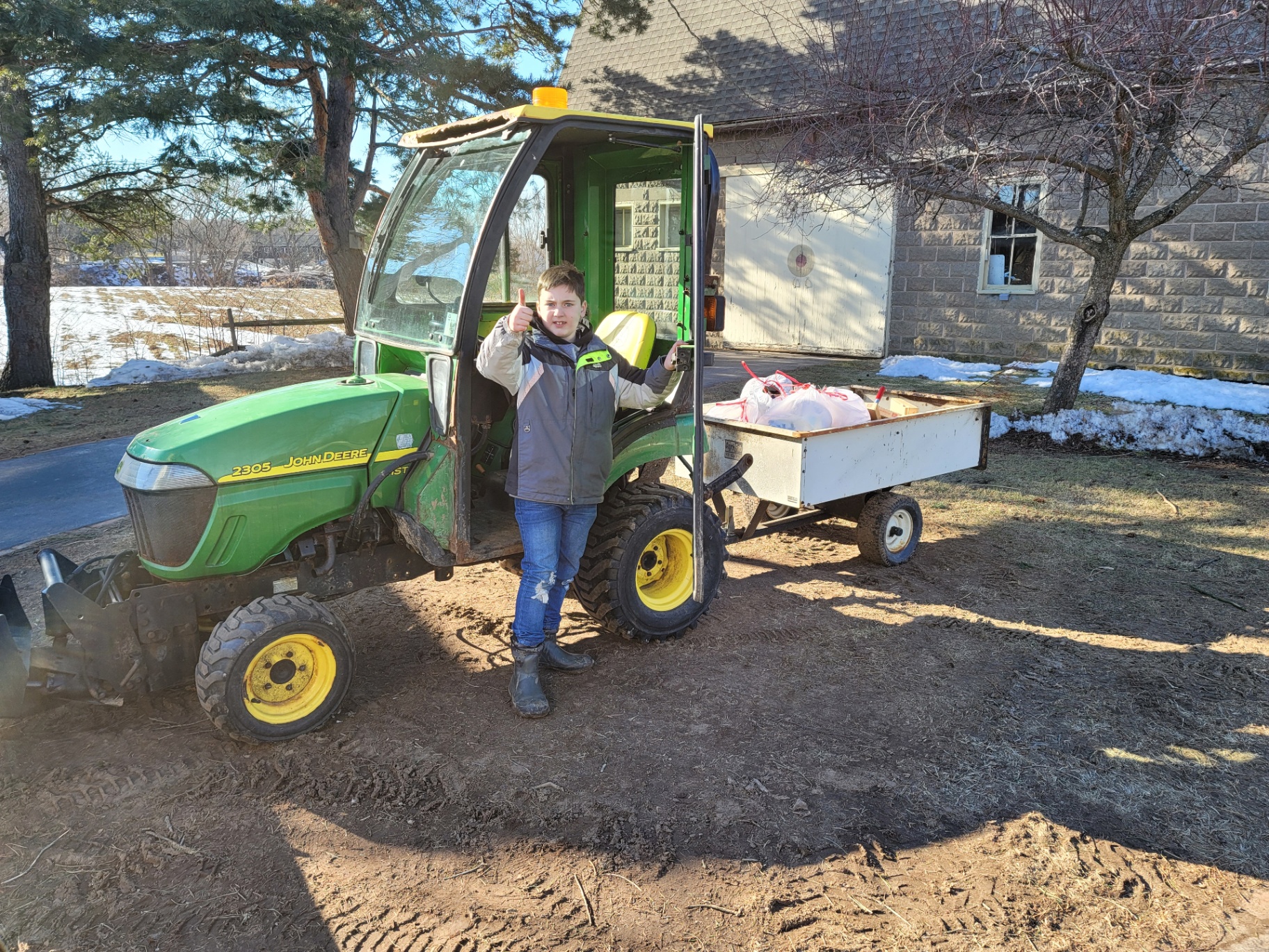 Casen giving a thumbs up next to a John Deere tractor